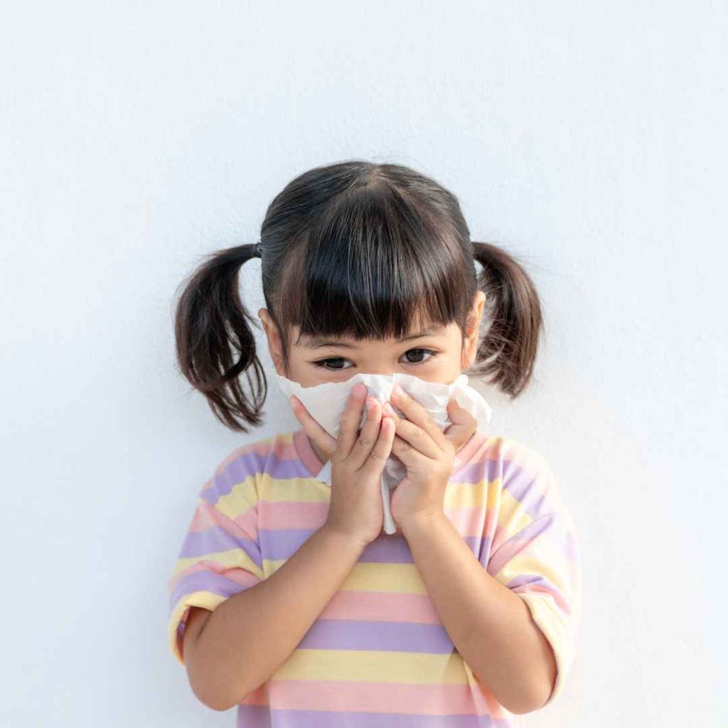 Anak perempuan menutup hidung dengan tisu saat flu dan batuk